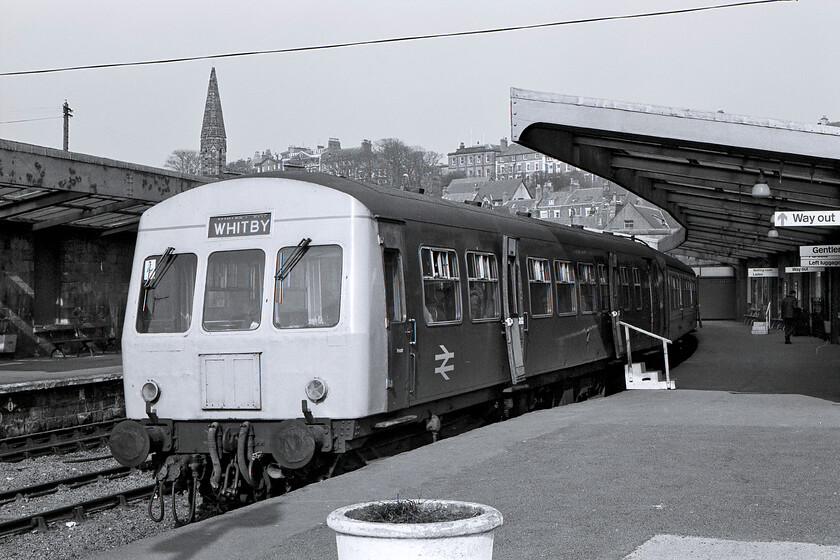 Class 101 DMU, unidentified working, Whitby station 
 A Class 101 DMU waits, hopefully, for passengers at Whitby station's platform two, the only one in use at this time. The DMU has crudely had its headcode panel plated over, a situation that would be rectified properly when this class were refurbished in the mid-1980s. Notice that the low platform requires the use of some wooden steps for some passengers. Today, this platform is now extended thus avoiding problems with its sharp curvature and is used for excursions and the regular workings from the North Yorkshire Moors Railway. Notice the spire of St. Hilda's Catholic church dominating the skyline. 
 Keywords: Class 101 DMU unidentified working Whitby station First generation DMU