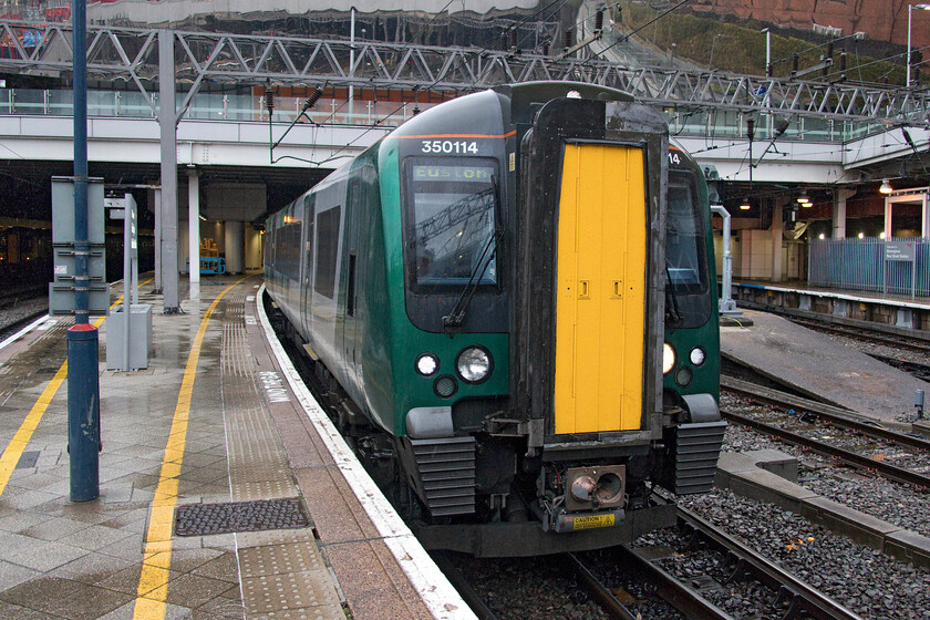 350114, LN 14.14 Birmingham New Street-London Euston (1Y26, RT), Birmingham New Street station 
 It may not look like it but it was absolutely pouring with rain when I ventured out on to the platform end at Birmingham New Street to take this photograph! Our third and final train home waits to leave New Street with the 14.14 service to Euston that we took as far as Northampton. The journey back was noted for the darkness that descended as we approached home with it being like evening and yet only being 15.00; I suppose that we were only a week or so off the shortest day though! 
 Keywords: 350114 14.14 Birmingham New Street-London Euston 1Y26 Birmingham New Street station London Northwestern Desiro