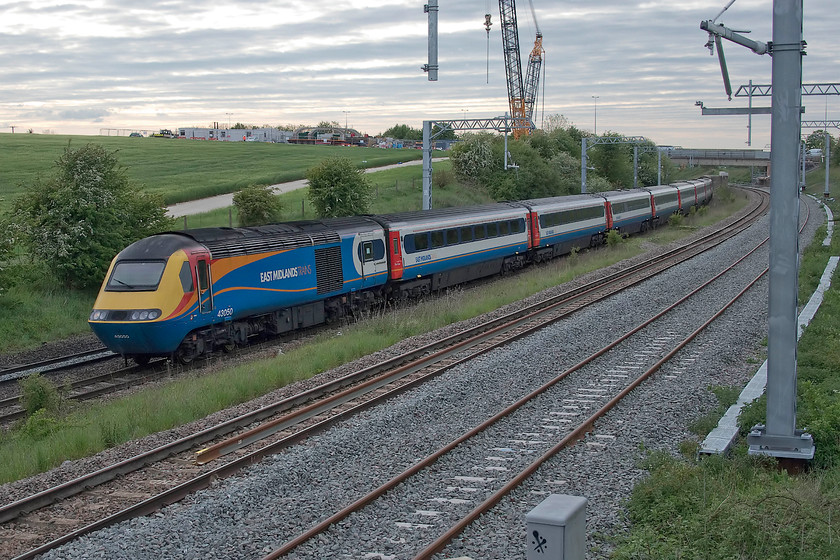 43050, EM 17.45 Nottingham-London St. Pancras (1B69, 4E), Irchester SP927667 
 With a dramatic sky after a run of beautiful spring days heralding a change in the weather at Irchester near Wellingborough on the MML. The 17.45 Nottingham to St. Pancras HST service is led by power car 43050. This power car was part of a number of extra ones introduced on to the Western Region in the summer of 1977 as part of set 253025. Notice the encampment at the top of the field in the background. This is associated with the extensive and somewhat disruptive works replacing the old A45 bridge in the distance. The original bridge that carried the westbound carriageways was the one being replaced it having been demolished a few weeks earlier forcing all traffic onto the eastbound bridge. 
 Keywords: 43050 17.45 Nottingham-London St. Pancras 1B69 Irchester SP927667