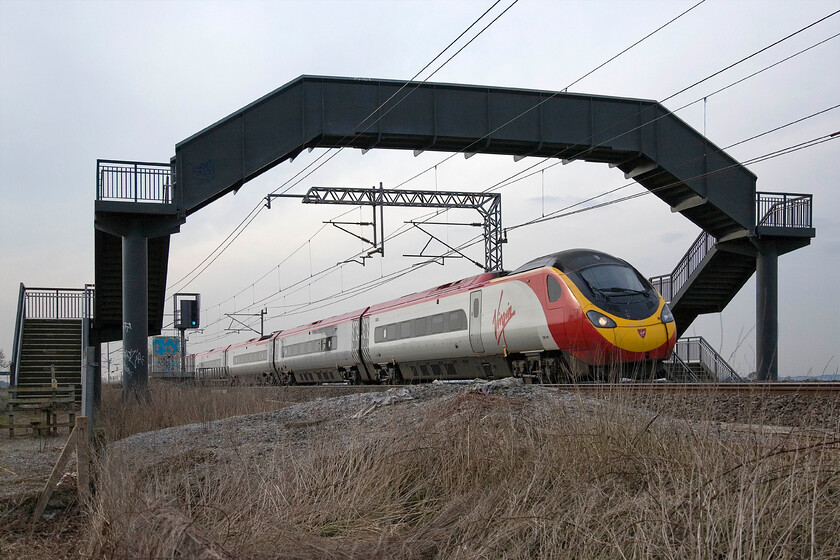 390118, VT 16.18 Liverpool Lime Street-London Euston, Milton crossing 
 390118 sweeps under a rather over-engineered footbridge that takes a little-used footpath over the WCML fast lines between the villages of Roade and Blisworth. I photographed the 16.18 Liverpool to Euston service whilst waiting for a returning footex from Wembley to Crewe. Alas, it was diverted away on to the Northampton loop line at Hanslope Junction so my teatime trip out was rather a waste of time. 
 Keywords: 390118 16.18 Liverpool Lime Street-London Euston Milton crossing Virgin West Coast Pendolino