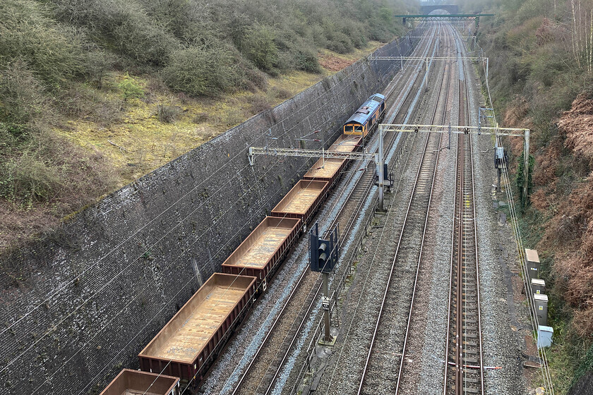 66768, infrastructure train, Roade cutting 
 Thankfully, 66768 had been switched off while it sits in Roade cutting leading a short rake of MHA Coalfish ballast wagons. The wagons were to be loaded with used ballast being 'vacuumed' up by a noisy Railvac machine out of sight to the left in this photograph. The ballast would then be transported to Bescot for cleaning, grading and then reuse elsewhere on the network. 
 Keywords: 66768 infrastructure train Roade cutting