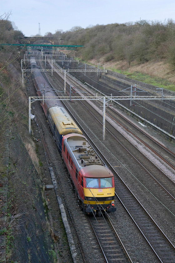 90029, 11.52 London Euston-Manchester Picadilly Footex (1Z90), Roade cutting 
 Looking smart, if a little grubby, in its DB livery, 90029 brings up the rear of the 11.52 Euston to Manchester Piccadilly footex special. These football specials were a common feature of the railways for many years but during the seventies, they gained a reputation for being a bit on the rough side with drunken hooligans wrecking trains hence why BR often wheeled out its oldest Mk. I stock! Today, whilst there are fewer football charters, they are a lot more civilised with fans enjoying a ride in some airconditioned Mk. IIf stock. 
 Keywords: 90029 11.52 London Euston-Manchester Picadilly Footex 1Z90 Roade cutting