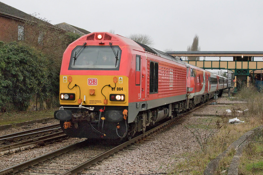 67004 & 82231, GR 10.45 Leeds-London Kings Cross (1A25, 9E), March level crossing 
 With a cheery wave from the driver and the pilot, 67004 leads 82232 working the 1A25 10.45 Leeds to King's Cross. The train is seen passing through March station and is about to cross the Station Road level crossing. I am standing on my stool to gain a little more height thus avoiding various things in the foreground such as relay boxes. As it had started to rain I decided to call it a day and head home. Obviously, as I was driving home the sun came back out in some style, I can only hope that, with the greatest respect, the sun did not shine on March! 
 Keywords: 67004 82231 10.45 Leeds-London Kings Cross 1A25 March level crossing