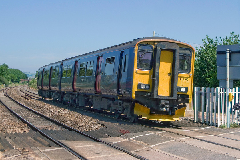 150246, GW 12.23 Bristol Temple Meads-Exeter St. David`s ecs (5E01), Bradford-on-Tone level crossing ST163232 
 150246 is climbing the lower slopes of Whiteball bank and is seen passing Bradford-on-Tone level crossing. The Sprinter is working the 12.23 Bristol to Exeter 5E01 empty coaching stock move. I stand to be corrected but I believe that there are actually no Sprinter or other services operated by units over this stretch of line. Unfortunately, I have had to take this photograph on the wrong side of the sun due to obstructions on the other side. Note my Raliegh Royal bike just putting in an appearance leaning against the fencing. 
 Keywords: 150246 12.23 Bristol Temple Meads-Exeter St. David`s ecs 5E01 Bradford-on-Tone level crossing ST163232 First Great Western Sprinter