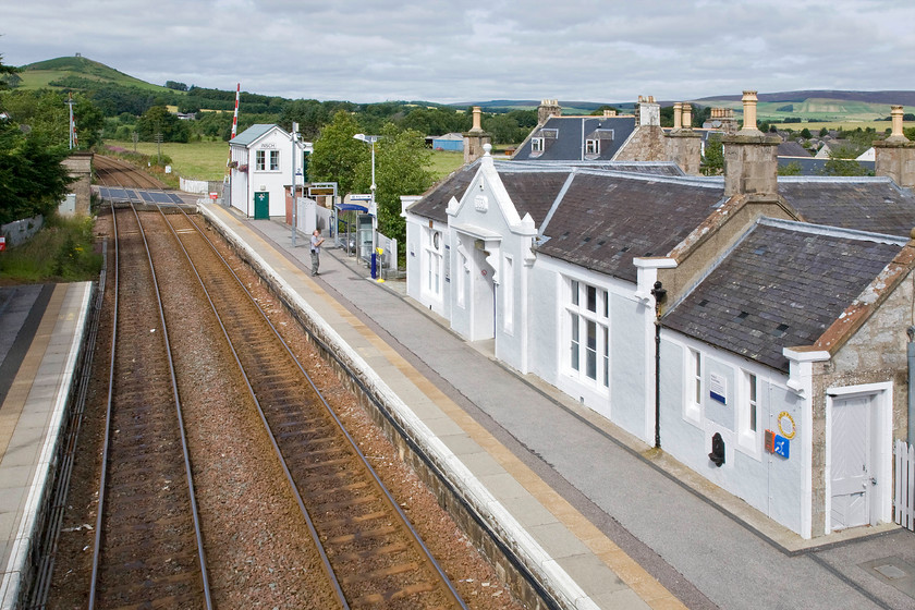 Insch station & signal box (GNS, 1886) 
 Taken from the station footbridge Andy inspects the delightful Insch station along with the signal box and the North Road level crossing. I have said it before but make no apologies for repeating it, ScotRail really do make an extra effort to maintain their stations and Insch is no exception. The station building is now home to the Insch Connection Museum, see..... http://www.inschmuseum.org.uk/ On the skyline atop the conical hill in the background are the remains of Dunideer Castle that is a popular local walking and visitor spot. 
 Keywords: Insch station signal box Great North of Scotland Railway GNS