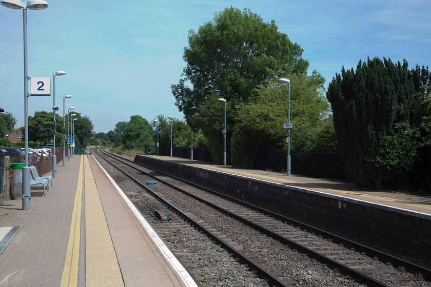 Bedwyn station, looking east 
 A strange picture to take but another one replicating on I took on my Exa camera in 1978. To the left where the cars are parked, was a small bay platform. In the middle distance, some way beyond the platform end was the GW signal box and the trees to the right are much bigger of course! The only other difference is that in the distance on my 1978 picture is that a Class 50 is seen approaching with a down express, see..... https://www.ontheupfast.com/p/21936chg/25327936604/x50029-down-working-bedwyn-station 
 Keywords: Bedwyn station