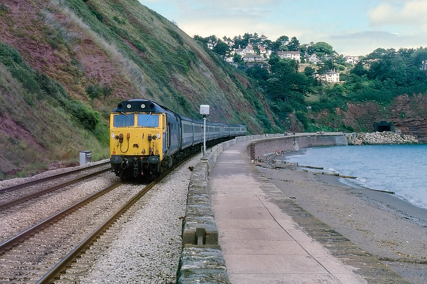 50013, 11.30 London Paddington-Penzance, the Cornish Riviera (1C77), Parson`s Tunnel 
 Halfway between Parsons Tunnel and Sprey Point, 50013 'Agincourt' is seen heading the down 1C77 Cornish Riviera that left Paddington for Penzance at 11.30. It is just passing the Teignmouth distant colour light. The properties above in the village of Holcome not only afforded a superb view of the coast but also of the IK Brunel built railway along the sea wall, perfect! 
 Keywords: 50013 11.30 London Paddington-Penzance the Cornish Riviera 1C77 Parson`s Tunnel