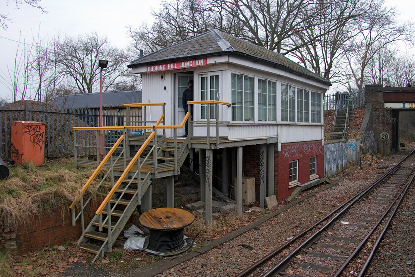 Dudding Hill Junction signal box (Mid, 1902) 
 This view of Dudding Hill Junction taken from the passing Verney Venturer charter shows the rather clumsy extension to the box added by Network Rail. It does not, however, disguise the original section of the Midland structure dating from 1902. I managed a photgraph of the box before it was 'modified' back during a visit to the area in 1979, see.... https://www.ontheupfast.com/p/21936chg/27444281004/dudding-hill-junction-signal-box Notice the signalman standing in the doorway of the box observing the passing of the charter hauled by a pair of Class 33s with a 47 for ETH purposes on the rear. He had probably been brought in to do the shift purely to signal the charter as no other traffic was scheduled to pass this way on this Saturday. 
 Keywords: Dudding Hill Junction signal box Midland 1902