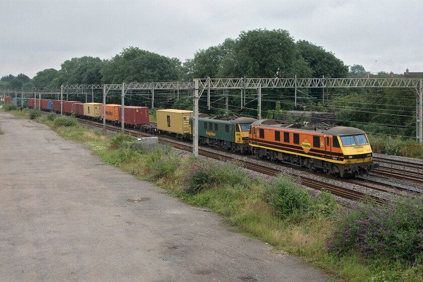 90044 & 90041, 02.50 Felixstowe North-Garston (4M45, 44E), site of Roade station 
 Wearing its parent company's Genesee & Wyoming livery 90041 leads 90044 in the more conventional Freightliner paint scheme. The pair of Class 90s are leading the 4M45 02.50 Felixstowe to Garston service past the site of Roade's former station. On what was a ridiculously dull August morning the bright orange and yellow colours certainly lift the lighting a little! 
 Keywords: 90044 90041 02.50 Felixstowe North-Garston 4M45 site of Roade station Freightliner