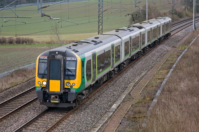 350244, LM 12.23 Bletchley CS-Rugby (5U33), Milton crossing 
 Due to the closure of the Northampton route London Midland were having to be creative with their services to avoid the dreaded 'bustitution' scenario for passengers. As part of their arrangements, they were running services starting from Rugby heading north to Birmingham, Crewe and Liverpool. In order to get the trains in the right place, 350244 is working the 5U33 12.23 Bletchley to Rugby empty stock move going via the Weedon line. It is seen passing Milton Crossing just north of Roade. 
 Keywords: 350244 LM 12.23 Bletchley CS-Rugby 5U33 Milton crossing London Midland Desiro