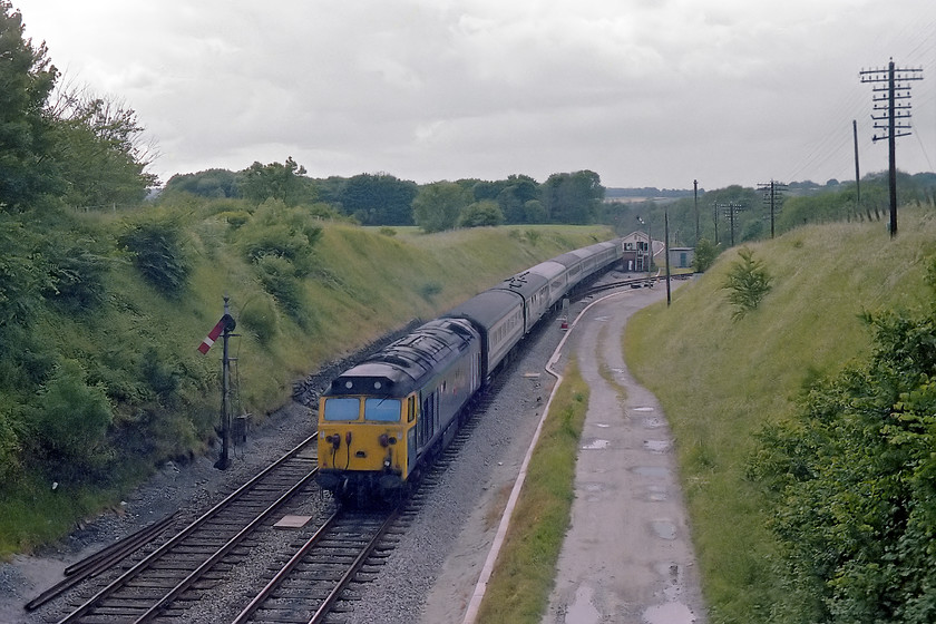 50002, unidentified up working, Savernake Junction 
 50002 'Superb' thrashes up Savarnake Bank and is about to breast the summit with an unidentified up working for Paddington. I visited this spot again in 2017 and very little could be seen as trees obliterated virtually everything apart from the trackbed itself. The track to the right is where the line that led to the bay platform of Savernake (Low Level) station used to be. The station itself, closed 18.04.66, was partially located directly under the bridge where I am standing. For such a rural location, there was also a Savernake (High Level) station, closed 15.09.61, on an avoiding line some 250 metres to my right such was the craziness of the politics of the Victorian and Edwardian railway companies. 
 Keywords: 50002 up working Savernake Junction