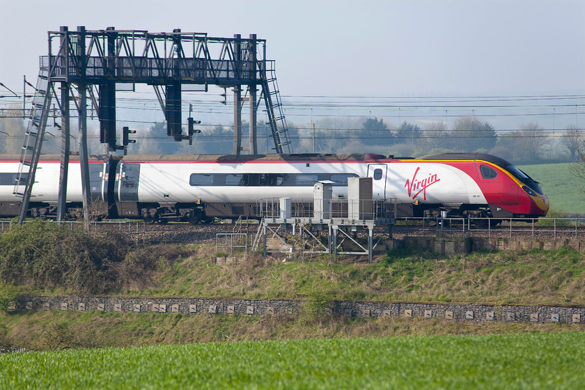 390107, LM 07.48 Liverpool Lime Street-London Euston (1A12, 1L), between Roade & Ashton 
 The rear of 390107 'Independence Day Resurgence' passes under the gargantuan signal gantry between Roade and Ashton just north of Hanslope Junction. Studying this structure carefully reveals that all it carries is a pair of twin light colour-lights for the up fast and slow lines. Quite why a structure of this size is needed for this is quite beyond me! This gantry can be seen from our bedroom window and the glow of its colour lights can bee seen clearly lighting up the countryside at night. 
 Keywords: 390107 1A12 between Roade & Ashton