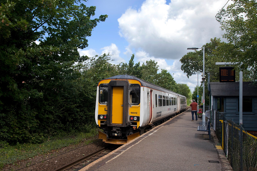 156412, LE 11.01 Marks Tey-Sudbury (2T12, 1E), Bures station 
 156412 arrives at Bures station working the 11.01 Marks Tey to Sudbury. Bures is located on the rote that Greater Anglia markets as the Gainsborough Line. It used to have a large station building situated where the first lamp post is. Looking at contemporary pictures of the building, it's clear that the small wooden waiting shelter in the foreground is the only remaining part of the building that has survived. 
 Keywords: 15642 2T12 Bures station