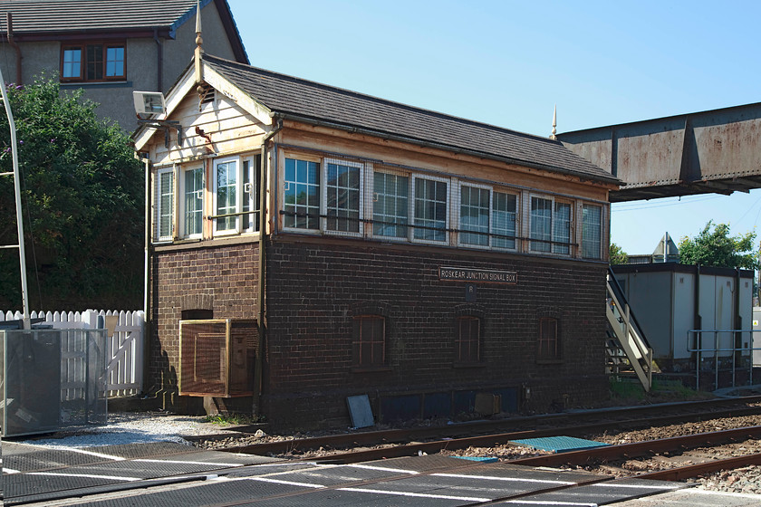 Roskear Junction signal box (GWR, c.1895) 
 Roskear Junction signal box, complete with a cast plate (possibly a reproduction?), stands in the morning summer sun. The box is situated in Camborne a short distance from the station at a level crossing. The box has the later shallower roof design and was constructed in about 1895. 
 Keywords: Roskear Junction signal box