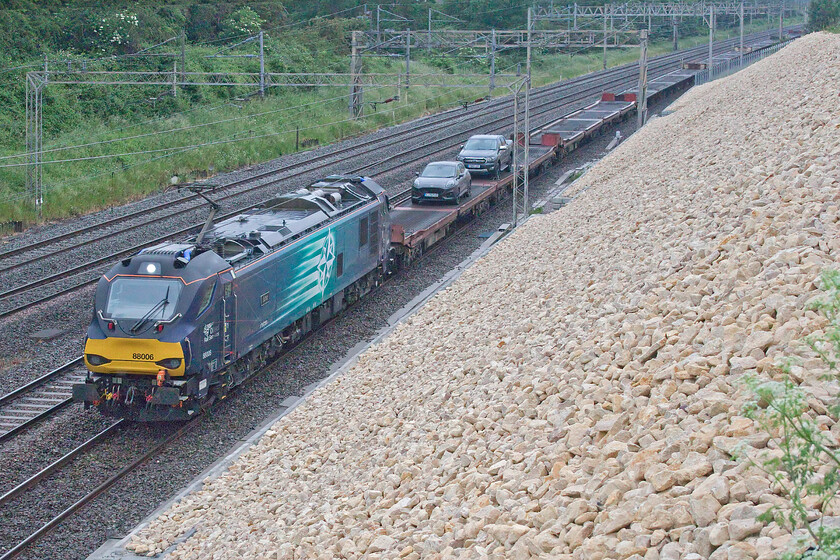 88006, 15.49 Garston-Dagenham (6L48, 4E), Ashton Road bridge 
 As an indication as to how grim the lighting is the headlight of 88006 'Juno' is shining out brightly leading the almost empty 6L48 15.49 Garston to Dagenham cartics. I say almost empty as it is carrying just two lone Ford models - a 70 plate Focus and a 69 plate Ranger. Quite why these two cars were being conveyed on this train will remain a mystery unless anybody can enlighten me? The train is seen just south of Roade about to pass under Ashton Road bridge. 
 Keywords: 88006 15.49 Garston-Dagenham 6L48 Ashton Road bridge Juno