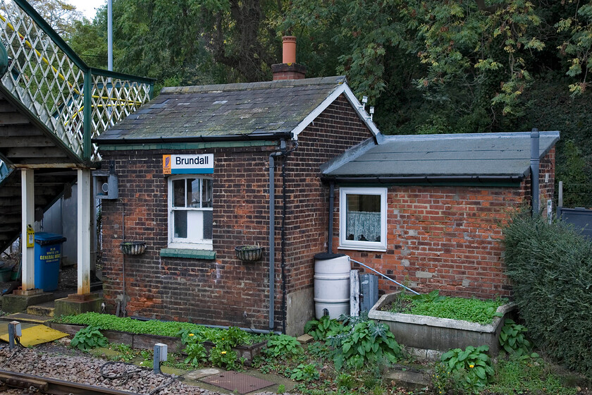 Brundall crossing box 
 This rather unassuming structure is the Brundall crossing keeper's box. It is manned twenty-four hours providing shelter for the crossing keeper. I cannot name very many examples of such an operation on the network. Notice the small extension to the building built of a slightly different brick and having a rather poor excuse for a roof that houses personal needs facilities for the crossing keeper. 
 Keywords: Brundall crossing box