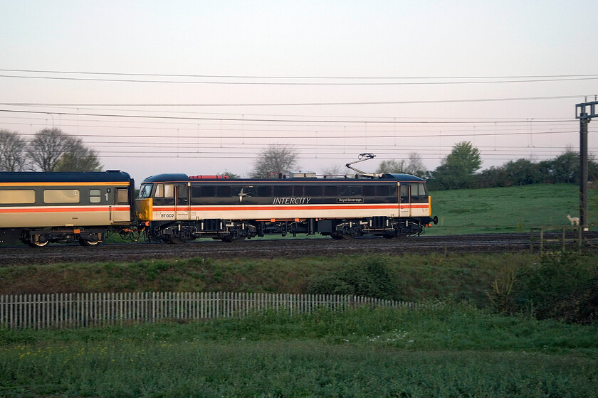 87002, 03.35 Crewe HS-London Euston (5Z90, 2E), between Roade & Ashton 
 Making light work at the rear of the six coach 5Z90 03.35 Crewe HS to Euston ECS move 87002 Royal Sovereign pushes the stock south between Roade and Ashton. A little later in the morning, the Class 87 would lead the stock north again as far as Crewe where steam would take the train on to Holyhead. LSL (Crewe) must be congratulated again for the way that they have prepared their stock reminding enthusiasts and the paying public of the railways of thirty years ago and perhaps a railway (state-run but sectorised) that many feel needs returning to having tried the deeply flawed privatised approach for too many years now! 
 Keywords: 87002 03.35 Crewe HS-London Euston 5Z90 between Roade & Ashton Intercity Swallow Royal Sovereign