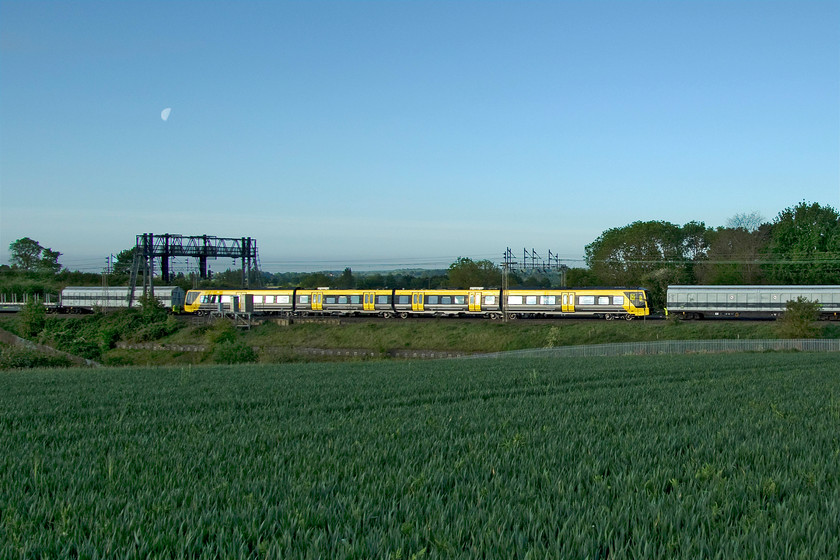 777004, 02.44 Dollands Moor-Kirkdale Carriage sidings (6X29, 2L) between Roade & Ashton 
 With a livery that is certainly quite a contrast to the lush spring greenery, Merseyrail 777004 passes on the down slow line between Roade and Ashton in Northamptonshire. It is continuing its journey from the Stadler factory at Bussnang, located in the northeast of Switzerland, to its new base at Kirkdale in Liverpool. The units should have been entering service by now but their introduction has been blighted by delays and, consequently, the first passengers will not use them for some time yet. This photograph was published in Rail edition 906. 
 Keywords: 777004 02.44 Dollands Moor-Kirkdale Carriage sidings 6X29 between Roade & Ashton Merseyrail Stadler