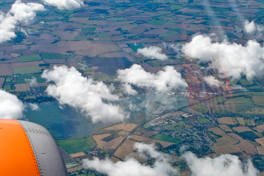 Manningtree, from EZY2446 
 Taken through the porthole window of easyjet flight EYZ2446 as we descend for our landing at Luton passing over Suffolk and Essex. In this view, the Stour estuary is seen with the village of Brantham in the foreground. Partly obliterated by the cloud is Manningtree. The GE mainline can clearly be seen curving from centre-bottom to centre-right crossing the twin courses of the Stour with Manningtree station just in view. 
 Keywords: Manningtree, from EZY2446 easyjet