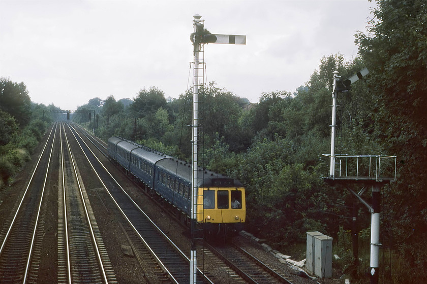 Class 127 DMU, unidentified up working, Radlett 
 A class 127 'Bed-Pan' DMU approaches Radlett station with an unidentified up working. It is about to pass two home signals, the one pulled off is the remaining arm on a bracket where the other signal permitted access to the old goods yard and shed. These Rolls-Royce engined DMUs were high density and fast accelerating sets that plied their trade their entire lives on this route until the electrification and the introduction of the 317 EMUs precipitated their withdrawal. The EMU's introduction was heavily delayed by a dispute with the unions over, you've guessed it, driver-only operation! 
 Keywords: Class 127 DMU Radlett