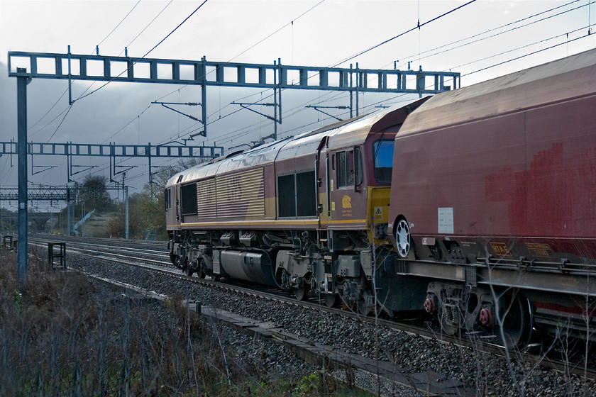 66126, 02.32 Peak Forest-Bletchley (6B10), Ashton Road bridge 
 The 02.32 Peak Forest to Bletchley stone train passes between Roade and Ashton some fourteen miles from its destination. The 6B10 freight utilises former coal wagons and on this day is hauled by 66126. I had to do with a 'going away' photograph as it is impossible to take a conventional image due to uncontrolled embankment growth. 
 Keywords: 66126 02.32 Peak Forest-Bletchley 6B10 Ashton Road bridge