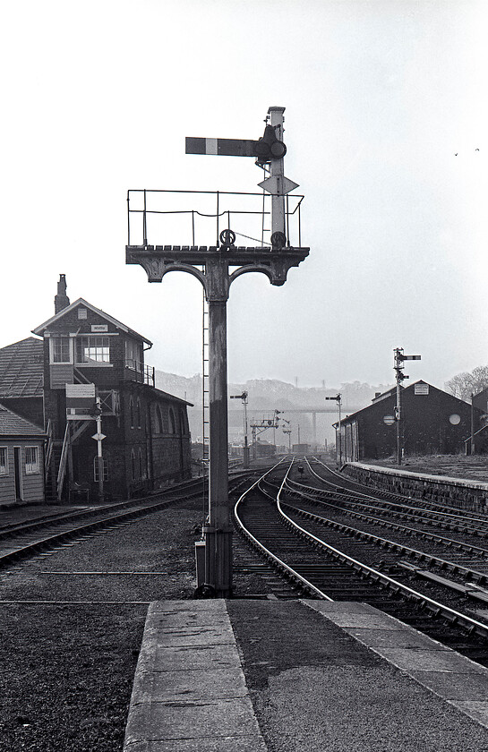 Signalling, Whitby station 
 The scene looking southeast from the platform end of Whitby station prior to the abolition of the mechanical signalling and the comprehensive rationalisation of the trackwork. The starter signal directly in front of the camera is a wooden post that is probably of North Eastern heritage the same as the 1876 signal box. Notice what is locally referred to as Whitby's new road bridge in the background spanning the Esk Valley that was opened a year or so earlier on 21.03.80. Looking into the afternoon autumn light and using Ilford FP4 monochrome film helps create an interesting atmosphere and one that I struggle to replicate on today's far too clever digital equipment! 
 Keywords: Signalling Whitby station