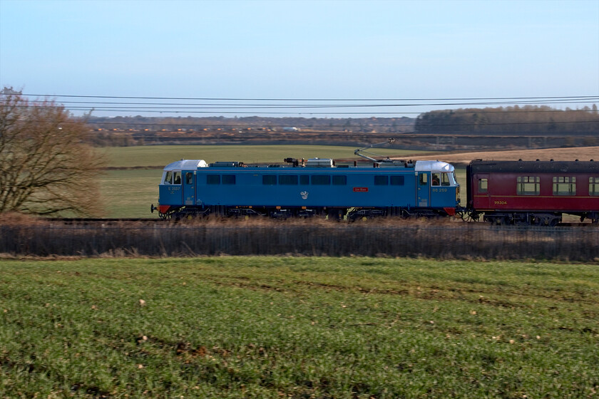 86259, outward leg of The Winter Cumbrian Mountain Express, 07.08 London Euston-Carlisle (1Z86, RT), Milton crossing 
 The second AC electric in thirty minutes to pass northwards along the WCML brings back memories of the pre-Pendolino era. 86259 'Les Ross/Peter Pan' leads the outward leg of The Winter Cumbrian Mountain Express charter from Euston to Carlisle that it led as far as Carnforth. Unfortunately, I did not get my calculations correct with the side of the train not quite illuminated by the rising sun, another week and it would probably have worked so Photoshop had to come to the rescue! 
 Keywords: 86259 The Winter Cumbrian Mountain Express 07.08 London Euston-Carlisle 1Z86 Milton crossing Peter Pan Les Ross