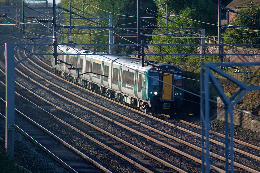 350267, LN 06.37 Northampton-Crewe (2U21, 2L), Little Bridgeford 
 Partially obscured by catenary 350267 heads northwards past the village of Little Bridgeford working the 06.37 Northampton to Crewe service. I was getting pretty desperate by this stage with just a short time before the arrival of the Deltic hauled charter. My attempts to get a fairly remote spot where a footpath crosses the line just south of Great Bridgeford had been thwarted by a lack of somewhere to park the car and a herd of cattle. Having found a parking spot some distance from where I wanted to be I started to cross the first of three fields when the cattle started massing and heading towards me at some speed so I turned heel and headed back! 
 Keywords: 350267 06.37 Northampton-Crewe 2U21 Worsten London Northwestern Desiro