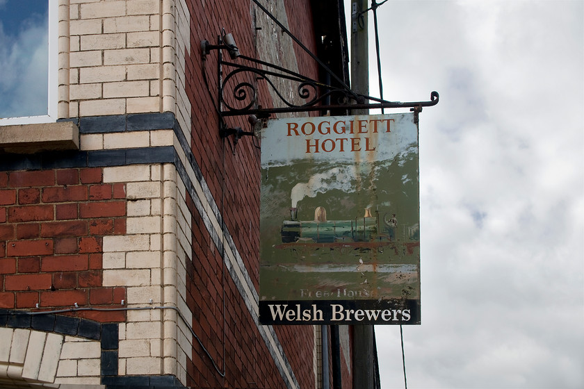 Pub sign, former Roggiett Hotel, Rogiet 
 The Roggiett Hotel was constructed at about the same time as the railway arrived at what is now known as Severn Tunnel Junction in around 1880. It is a large hotel and pub for the size of the village of Rogiet. Notice the different variation of the spelling of the village, the pub bears the traditional version while the contemporary version is Rogiet. The hotel and pub closed in 2007 only to be re-opened again by a well-intentioned band of locals who, unfortunately, could not make a go it with it closing again in 2010. Nine years later, it is still empty, boarded up and looking very sorry for itself. It is located two minute's walk from Severn Tunnel Junction station on Station Road but still bears its pub sign. The rather faded image purports to be of a GWR 2-4-0 engine dating from circa 1850 but, I am happy to be advised further on this. 
 Keywords: Pub sign former Roggiett Hotel Rogiet