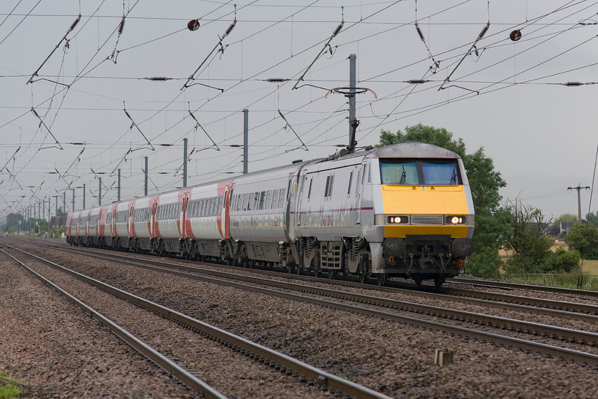 91118, GR 08.00 London King`s Cross-Edinburgh (1S07), Holme Green crossing TL192426 
 This IC225 set is nearly there with regard to its transformation from East Coast Trains to Virgin East Coast! The leading locomotive and Mk. IV coach is still in the old colours whilst the rest of the set wears its smart new look. The 1S07 08.00 King's Cross to Edinburgh passes Holme Green crossing near the village of Langford being led by 91118. 
 Keywords: 91118 08.00 London King`s Cross-Edinburgh 1S07 Holme Green crossing TL192426 IC225 Virgin East Coast