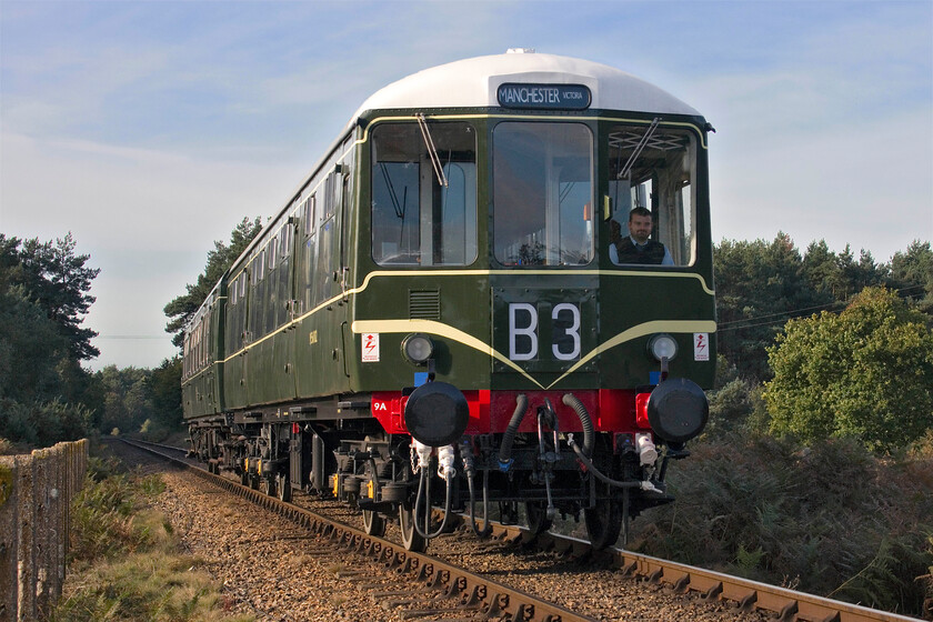 M56182 & M51188, 10.20 Holt-Sheringham, Windpump crossing Kelling Heath-17.10.23 
 Looking resplendent in the morning sunshine Class 104 M56182 leads Class 101 M51188 across Kelling Heath taken at Windpump crossing. Contrary to the Manchester Victoria destination blind the train is actually heading for Sheringham having left Holt at 10.20. In this light it is clear to see the standard of the huge restoration that the Driving Trailer Composite Lavatory (non-powered) DMU carriage has undergone with its authentic speed whiskers and white roof really looking the part. I can also vouch that the standard of the interior was as good as the outside looks; a magnificent achievement and a credit to all involved. 
 Keywords: M56182 M51188 10.20 Holt-Sheringham Windpump crossing Kelling Heath First generation DMU Class 101 Class 104