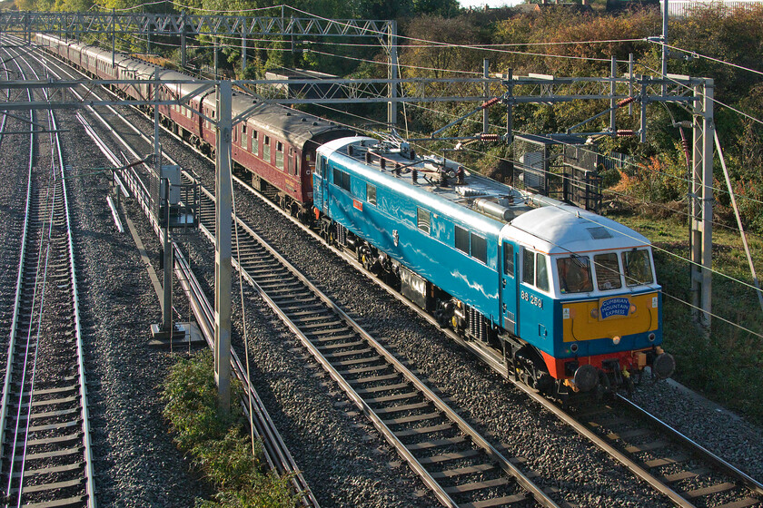 86259, outward leg of The Cumbrian Mountain Express, 07.15 London Euston-Carlisle (1C96, 20L), site of Roade station 
 Running some forty minutes late, time it did not fully recover, 86259 'Les Ross/Peter Pan' passes Roade leading the outward Cumbrian Mountain Express charter. This photograph is rather strongly backlit, a situation that would have been a lot better if the train had been running to time! The 07.15 Euston to Carlisle was hauled by the ac electric as far as Carnforth where 35018 'British India Line' was to take over for the journey north over Shap with 47804 assisting at the rear. 
 Keywords: 86259 The Cumbrian Mountain Express 07.15 London Euston-Carlisle 1C96 site of Roade station Les Ross Peter Pan AX electric AL3