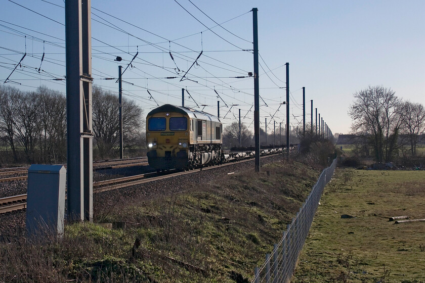 66564, 10.49 London Gateway-Leeds FLT (4E24, 7L), Holme Green crossing TL192426 
 Hauling an awful lot of fresh air 66564 makes its way along the down slow line at Holmes Green between Biggleswade and Arlesey. The Class 66 would have been making very easy work of the 10.49 London Gateway to Leeds Freightliner Terminal. I make no apologies for the unusual positioning of the locomotive in this photograph dictated somewhat by the low afternoon sun and the lack of clear access caused by the positioning of electrical masts! 
 Keywords: 66564 10.49 London Gateway-Leeds FLT 4E24 Holme Green crossing TL192426 Freightliner