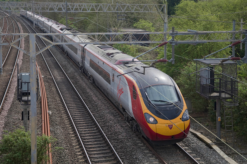 390138, VT 12.30 London Euston-Glasgow Central (1S63, 1L), site of Roade Station 
 390138 'City of London' approaches the site of the old Roade station working the 12.30 Euston to Glasgow Central. I am standing on a footbridge that spans the line that stood atop the ends of the platforms of the old station that closed on 07.09.64. This scene, looking south, was very different before closure. There were numerous sidings to the right, Roade signal box and a link up to the Stratford-upon-Avon and Midland Junction Railway (SM &J) that crossed the LMS lines about half a mile south from this spot on a girder bridge. 
 Keywords: 390138 1S63 site of Roade Station