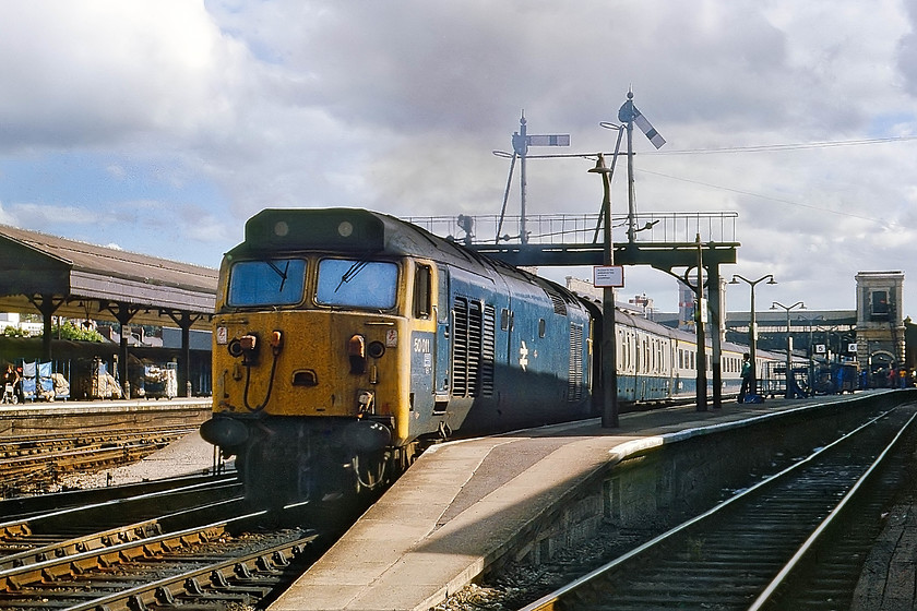 50011, 15.01 Penzance-London Paddington, Exeter St. David`s station 
 I arrived at Exeter St. Davids just in time to see 50011 leading the 15.01 Penzance to London Paddington leaving the station. This 50 was the penultimate to be named and, in July 1987, was the first to be withdrawn. It is seen at the northern end of St. Davids Station from the level crossing just in front of Exeter Middle signal box. The level crossing was extremely busy, straddling all the lines in the throat of the station and was controlled by the box but a further member of the railway staff controlled the separate pedestrian crossing. He had a small hut at the foot of the main box and could always be seen in his hi-vis waistcoat about the crossing area. 
 Keywords: 50011 15.01 Penzance-London Paddington Exeter St. David`s station