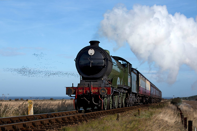 8572, 10.30 Sheringham-Holt, Weybourne TG123424 
 Having just crossed the A149 coast road, ex. LNER B12 4-6-0 8572 opens up for the rising gradient as it heads towards Weybourne station leading the 10.30 Sheringham to Holt. This loco. is owned by the M&GN society and is absolutely superb and in-keeping for this particular line. The M&GN milepost to the left of the engine is showing 40 miles from South Lyn Junction in King's Lyn via Fakenham. Also notice the huge skein of geese that have taken flight being spooked by the passing of the train; the noise that they made was incredible and added a certain something to the DAT recording that I undertook of the train. 
 Keywords: 8572 10.30 Sheringham-Holt Weybourne TG123424