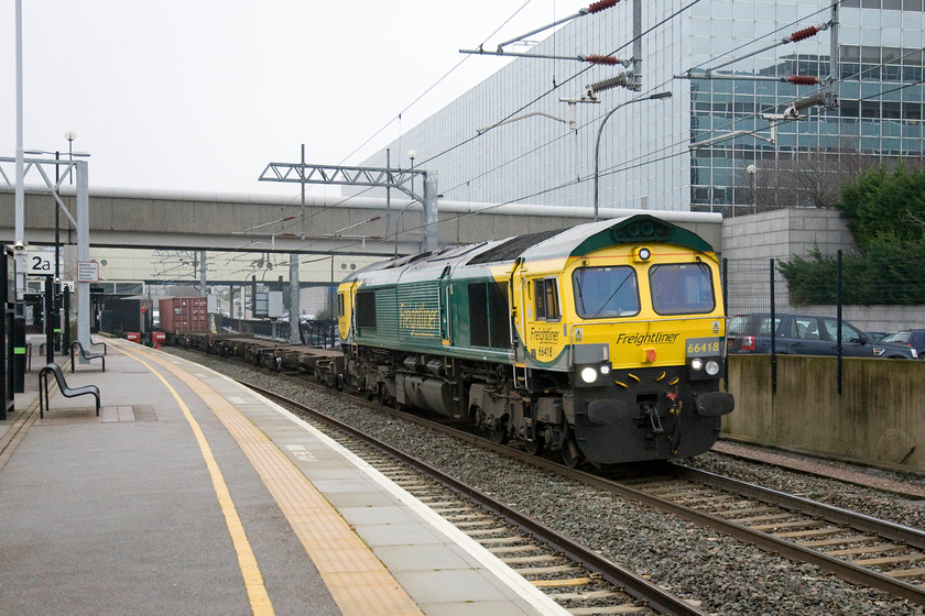 66418, 05.01 Trafford Park-Felixstowe North (4L97), Milton Keynes Central station 
 66418 passes through Milton keynes station with the 4L97 05.01 Trafford Park to Felixstowe Freightliner working. The revised Freightliner livery as applied here with its much increased use of yellow on the front ends certainly lifts these locos. out of the drab scenery on a dull day such as this. 
 Keywords: 66418 05.01 Trafford Park-Felixstowe North 4L97 Milton Keynes Central station