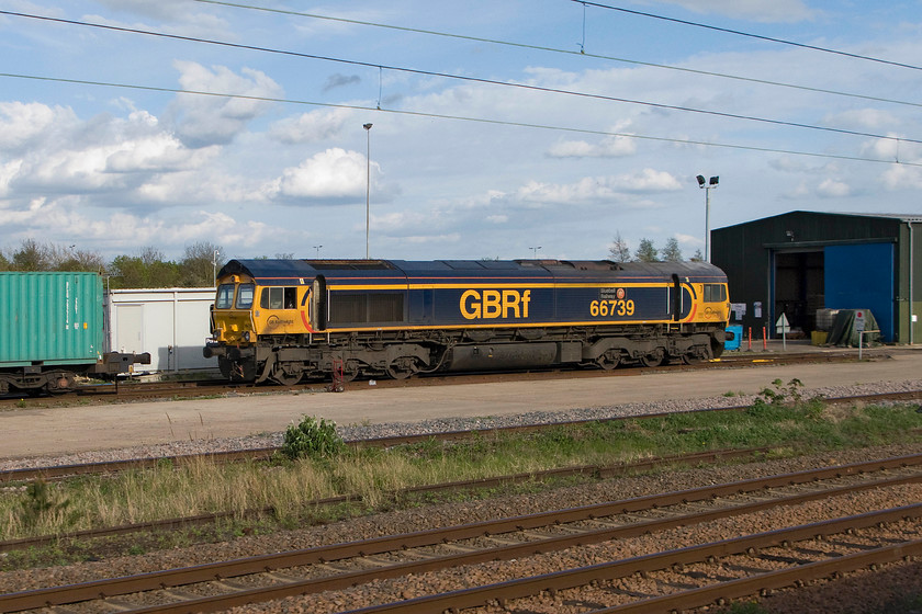 66739, stabled, Peterborough yard 
 The site of the former Peterborough diesel depot (PB) is still in use today as a maintenance facility for freight operator GBRF. As we approach the station 66739 'Bluebell Railway' is seen stabled on one of the depot roads awaiting attention. 
 Keywords: 66739 Peterborough yard Bluebell Railway