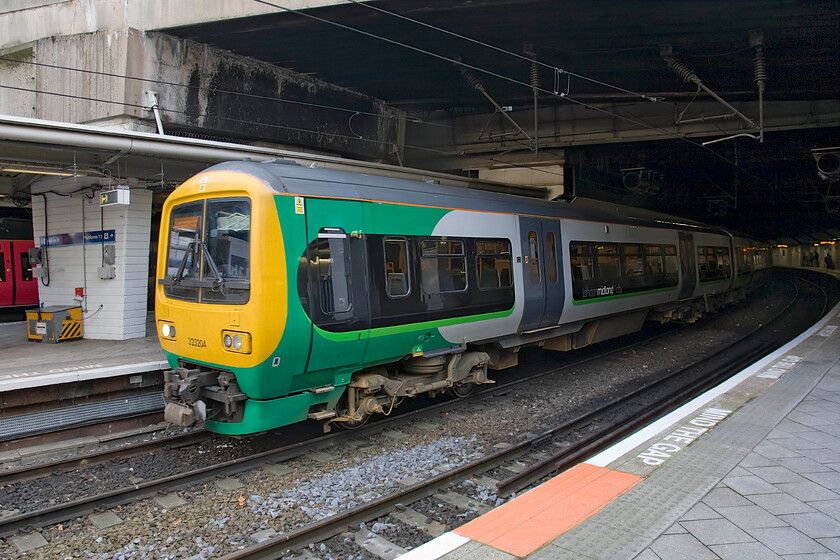 323294, LM 09.43 Lichfield City-Longbridge (2N39), Birmingham New Street station 
 London Midland City's 323294 pokes its nose out of the gloom at Birmingham New Street station. It is pausing working the cross-city 09.43 Lichfiled City to Longbridge 2N39 service. These excellent and reliable units are fairly elderly now and are ready for replacement, something that should be happening in the next few years along with the planned expansion of electrification. 
 Keywords: 323294 09.43 Lichfield City-Longbridge 2N39 Birmingham New Street station London Midland City