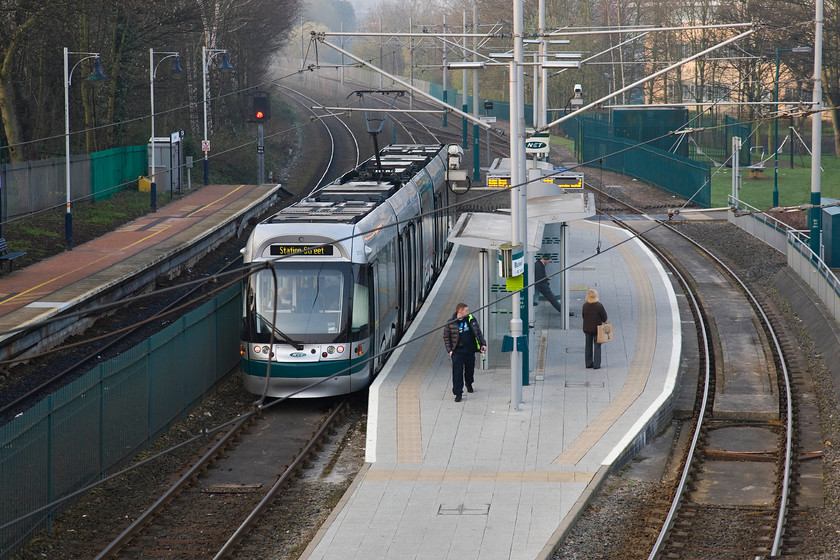 203, (NET) 07.14 Hucknall-Station Square, Bullwell station 
 In the light mist of a spring morning, Nottingham Express Transit unit 203 leaves Bullwell station with the 07.14 Hucknall to Station Square service. This particular tram is the second numbered of the initial order of Incentro AT6/5 units. These were built by Bombardier Transportation and introduced to service in 2004. Notice the heavy rail track to the left and the platform that serves the Robin Hood line that at this point is a single track. 
 Keywords: 203 NET 07.14 Hucknall-Station Square Bullwell station