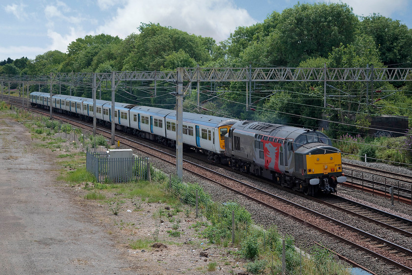 37884, 319423 & 319430, 10.42 Hornsey-Long Marston (5M94), site of Raode station 
 Running late now but, at least still running! 37884 tows off-lease 319423 and 319430 as the 10.42 Hornsey Depot to Long Marston. The 5M94 working was a regular one that involved the dragging of the 319s not selected for further use with Northern for storage pending a decision upon their future. The train is seen passing the site of Roade station. 
 Keywords: 37884 319423 319430 10.42 Hornsey-Long Marston 5M94 site of Raode station