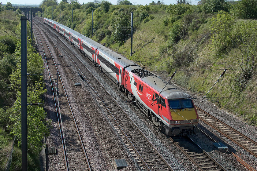 91107, GR 08.33 London King`s Cross-Leeds (1D06, 34L), Essendine TF043129 
 91107 'Skyfall' leads the 08.33 King's Cross to Leeds service past Essendine as it commences the climb of Stoke Bank, a steady 1:200 for about twelve miles. This service, along with most on this day was running late due to issues in the Stevenage area, this train arrived at Leeds thirty-four minutes down. I have visited this spot a number of times over the years, not least when the Deltics were in operation The scene was somewhat different back in 1980, see...... https://www.ontheupfast.com/p/21936chg/29682538204/x3-55-011-08-05-london-king-s-cross 
 Keywords: 91107 08.33 London King`s Cross-Leeds 1D06 Essendine TF043129