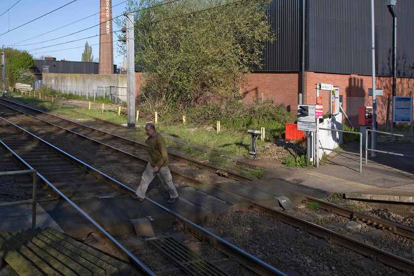 Andy using the flat crossing, Mistley station 
 Flat crossings on the national network are becoming increasingly rare as Network Rail pusses ahead with it obsessive compulsion to remove every one. In order to irradicate this one at Mistley station, a footbridge will be required at great cost so I suspect that Andy would be able to cross the line at this point for some years to come yet! In the background is the 1932 constructed chimney on the former Edme foodstuffs production site that has now closed and moved elsewhere. The chimney is now a listed structure and a major landmark in the area. Despite this, there have been repeated moves to demolish it but non of the plans have been successful. 
 Keywords: Andy using the flat crossing Mistley station