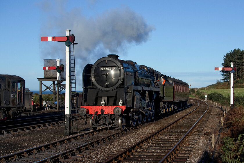 92203, going on-shed, Weybourne station 
 In strong sunshine, I always find the photographing of black locomotives such as 9F 2-10-0 92203 'Black Prince' tricky with the bulk of the superstructure being very dark with no detail evident. As my readers know well, I like to expose my photographs with care concentrating on the background and the sky first then working on the subject, often as two completely separate digital layers. With a superb background with rich colouring in the sky, sea and the field to the right there are still details of the locomotive that are too dark even after spending some time 'working' the image in Photoshop. It is seen arriving at Weybourne from Sheringham with just one coach that is perhaps returning for attention following the ending of services for the day? 
 Keywords: 92203 going on-shed Weybourne station Black Prince 9F 2-10-0