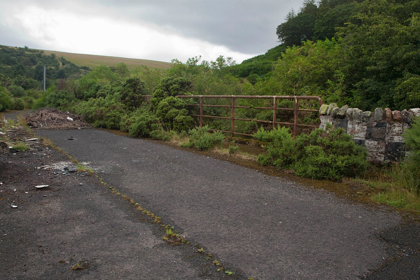 Former A1 road bridge just south of Penmansheil tunnel mouth NT796569 
 In the foreground is the former course of the A1 road and the bridge that carried it across the ECML at Penmansheil. The entrance to the old tunnel in the trees directly behind the rather flimsy bridge parapet. On the night of 10th March 1979, the roof of the tunnel collapsed whilst engineering works were being undertaken to lower the level of the track to enable 2.59m high containers to travel through it on intermodal wagons. Unfortunately, two local workers were killed in the collapse and it was decided not to reopen the tunnel, thus their bodies were never recovered. Work on the diversion of the railway started on 7th May and was completed on 20th August. The A1 was also re-aligned with both the road and railway travelling side by side for just over a kilometre. It is quite remarkable that this task was completed by Mcalpine and BR in just over three months, could one imagine this happening today, the planning inquiry alone would take longer than that! 
 Keywords: Former A1 road bridge just south of Penmansheil tunnel mouth NT796569