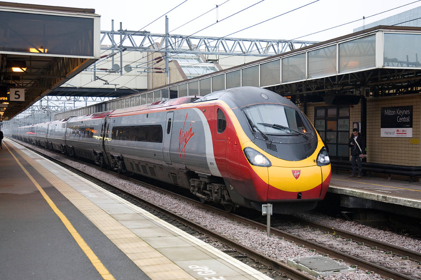 350115, VT 09.15 Manchester Piccadilly-London Euston (1A17), Milton Keynes Central station 
 390115 slows for its stop at Milton Keynes with the 1A17 09.15 Manchester Piccadilly to London Euston. As it was stopping, it was easy to identify its number and use a reasonably slow shutter speed with a sensible ISO on the camera with little subsequent digital noise. 
 Keywords: 350115 09.15 Manchester Piccadilly-London Euston 1A17 Milton Keynes Central station