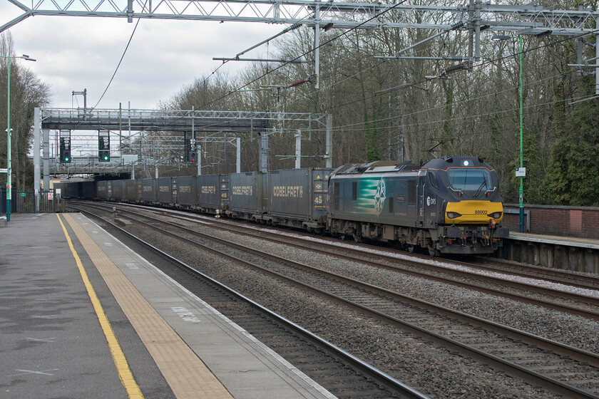 88002, 05.46 Mossend Down Yard-DIRFT (4M27, 6E), Atherstone station 
 Doing what it was designed and what they do so well, namely hauling one of the Anglo-Scottish Tesco Express services 88002 'Prometheus' passes through Atherstone station. The 4M27 05.46 Mossend to Daventry was well loaded having taken just over six hours to reach this point in Warwickshire with just twenty minutes or so left before arriving at DIRFT. These fast locomotives have proved to be reliable and efficient in service and must represent a good choice for DRS back in 2012 when the process of procurement began. 
 Keywords: 88002 05.46 Mossend Down Yard-DIRFT 4M27 Atherstone station Prometheus DRS Direct Rail Services