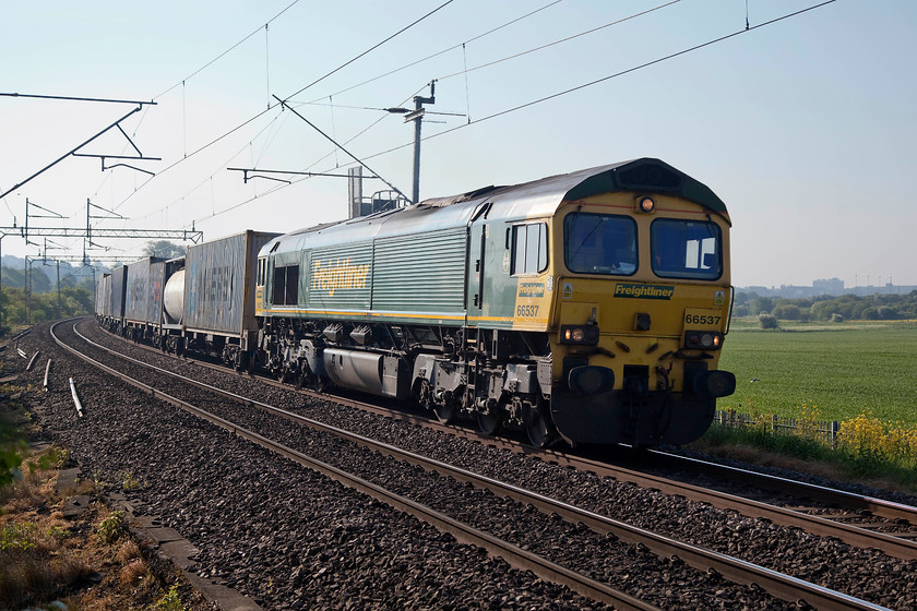 66537, 04.25 Felixstowe-Lawley Street (4M88), Wilson s Crossing 
 Heavily back lit but a freight is a freight! 66537 heads the 4M88 04.25 Felixstowe to Lawley Street Freightliner out of Northampton past Wilson's Crossing. This is flat crossing just north of Northampton that is under constant threat of closure, persistent local pressure has kept it open....for the moment! 
 Keywords: 66537 4M88 Wilson's Crossing