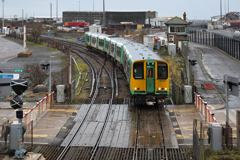 313207, SN 15.53 Seaford-Brighton (2C45, 1E), Newhaven Harbour-station 
 In this fascinating view 313207 is about to cross the doomed level crossing at Newhaven Harbour station with the 15.53 Seaford to Brighton service. Also in this picture is Newhaven Harbour signal box that is also doomed with both only having three weeks left in use before closure and decommissioning. The new signalling is seen under plastic bags with tape crosses to the left and the old machinery to be removed daubed with green crosses. 
 Keywords: 313207 15.53 Seaford-Brighton 2C45 Newhaven Harbour-station