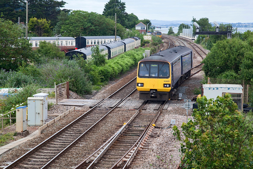 143620, GW 15.53 Exmouth-Paignton (2T22, 2L), Dawlish Warren SX979783 
 A picture full of interest! Apart from 143620 leaving Dawlish Warren with the 15.53 Exmouth to Paignton service, the famous camping coaches can be seen. There have been camping coaches at this location since the 1930s with their fortunes having waxed and waned over the intervening time. At the time of writing, the coaches are operated by the Brunel Holiday Park. Also of interest is the structure on Dawlish Warren's up platform that resembles a signal box. This is a private residence that has been built in the style of a traditional box and a very good job has been done. The original box, that was dismantled in 1990, was at the far end of the down platform. The train is about to pass under the 1873 GWR footbridge and is passing the site of the first station here named Warren Hat and after that Warren Platform before the present-day station was opened in 1912. 
 Keywords: 143620 2T22 Dawlish Warren SX979783